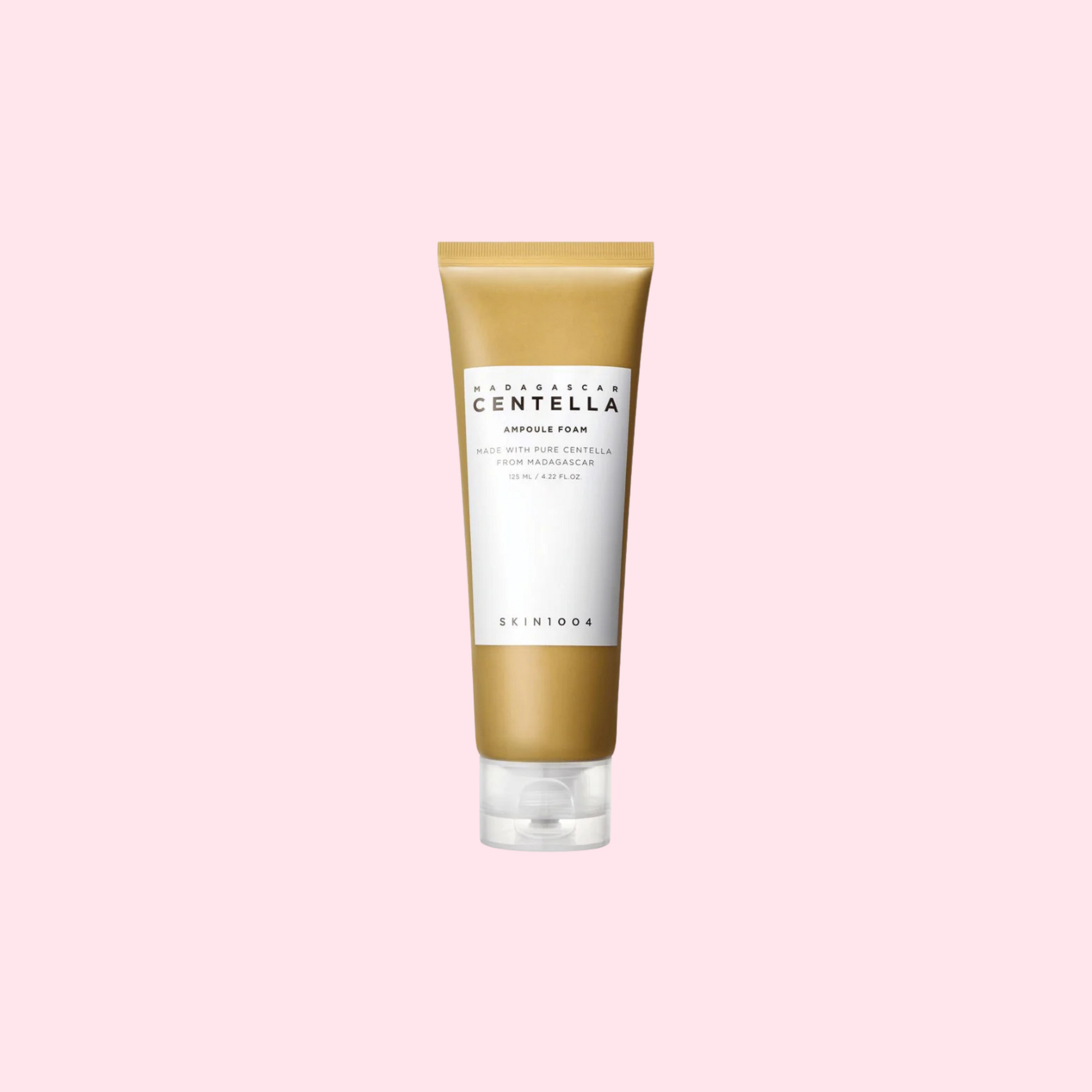 Produktbild av SKIN1004 Madagascar Centella Ampoule Foam i en 125 ml tub. Förpackningen är guldig med vit etikett och text i svart, stående mot en ljusrosa bakgrund.